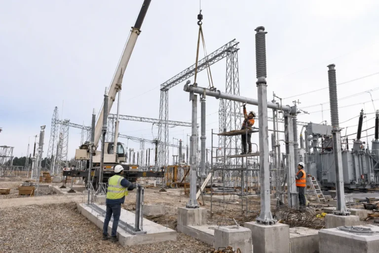 Workers installing high-voltage substation equipment with a crane at a 500kV project site